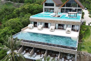 Una piscina al aire libre, sombrillas, sillones reclinables de piscina