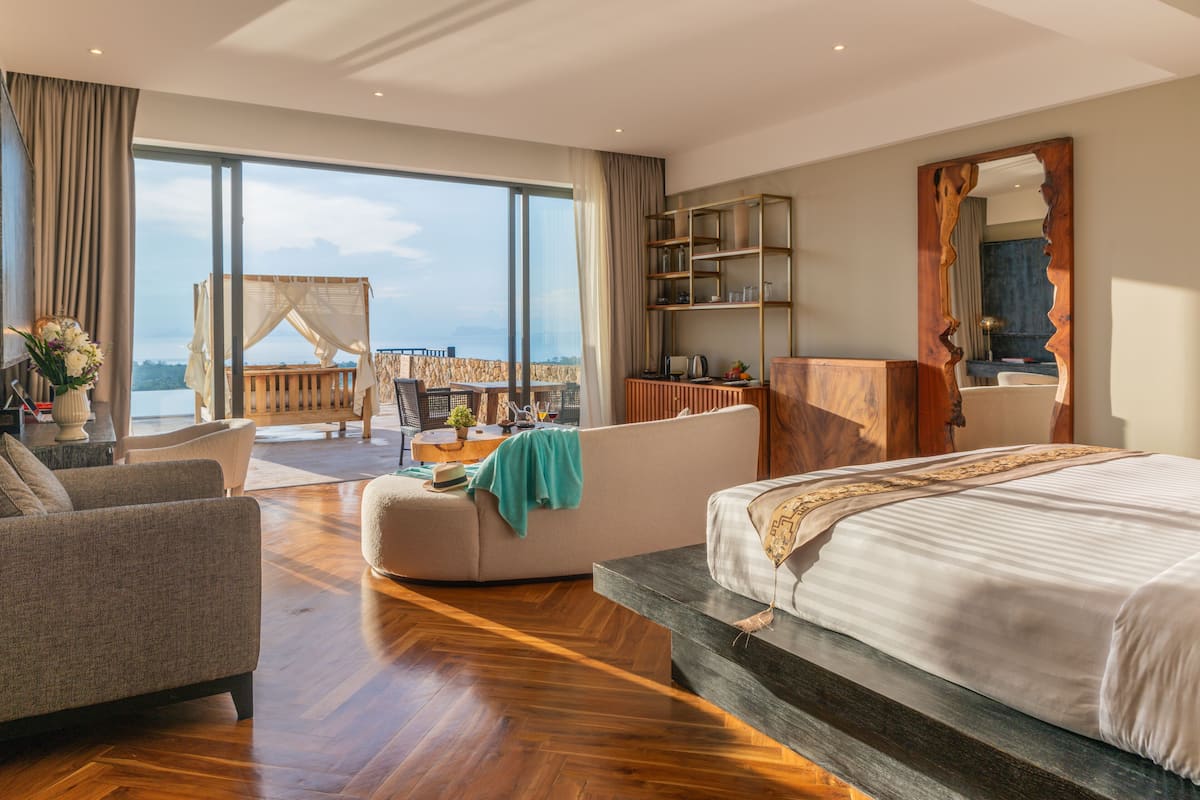 Une chambre d’hôtel moderne dotée d’un grand lit, d’un canapé, d’un bureau et d’un balcon avec vue.