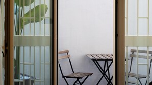 Een kamer met een schuifdeur naar een balkon met een tafel en stoelen.