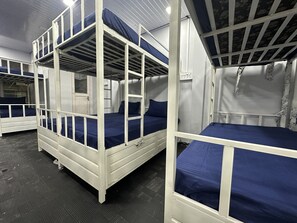 Un dormitorio con literas, una ventana pequeña y una puerta.