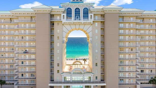 A hotel with a central archway leading to a beach view, multiple balconies, and a symmetrical facade. - Majestic Sun A1104* Beachfront (Miramar Beach)
