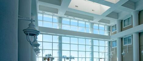 An indoor swimming pool with a view of the ocean, large windows, and a high ceiling.