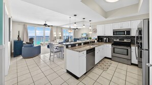 A spacious kitchen with white cabinets, a central island, and a view to the outside. - Majestic Sun A1104* Beachfront (Miramar Beach)