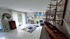 A spacious living room with a large wooden ship model, a patterned rug, and a view of the outdoors through a large window. - Charmante Hausvilla in Bojendorf (Bojendorf)