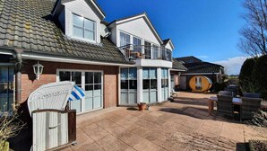 A two-story house with a balcony, a garage, and a patio area with outdoor furniture. - Charmante Hausvilla in Bojendorf (Bojendorf)