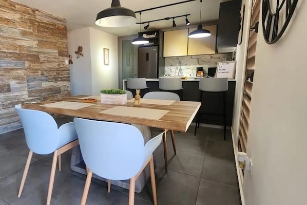 Un espace de salle à manger moderne avec une table en bois, des chaises bleu clair et des luminaires suspendus.