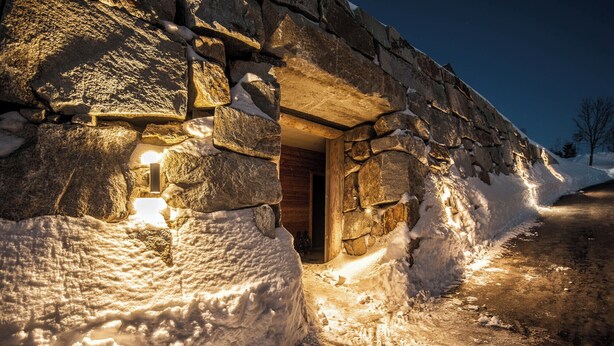 Ein Steinhaus mit Holztür, umgeben von Schnee.