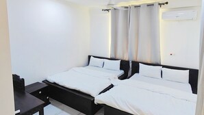 Un dormitorio con dos camas, un escritorio y un equipo de aire acondicionado.