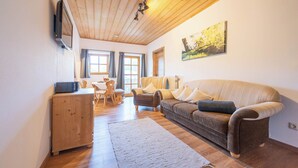 Una sala de estar acogedora con techo de madera, un sofá, una mesa de centro y un cuadro en la pared.