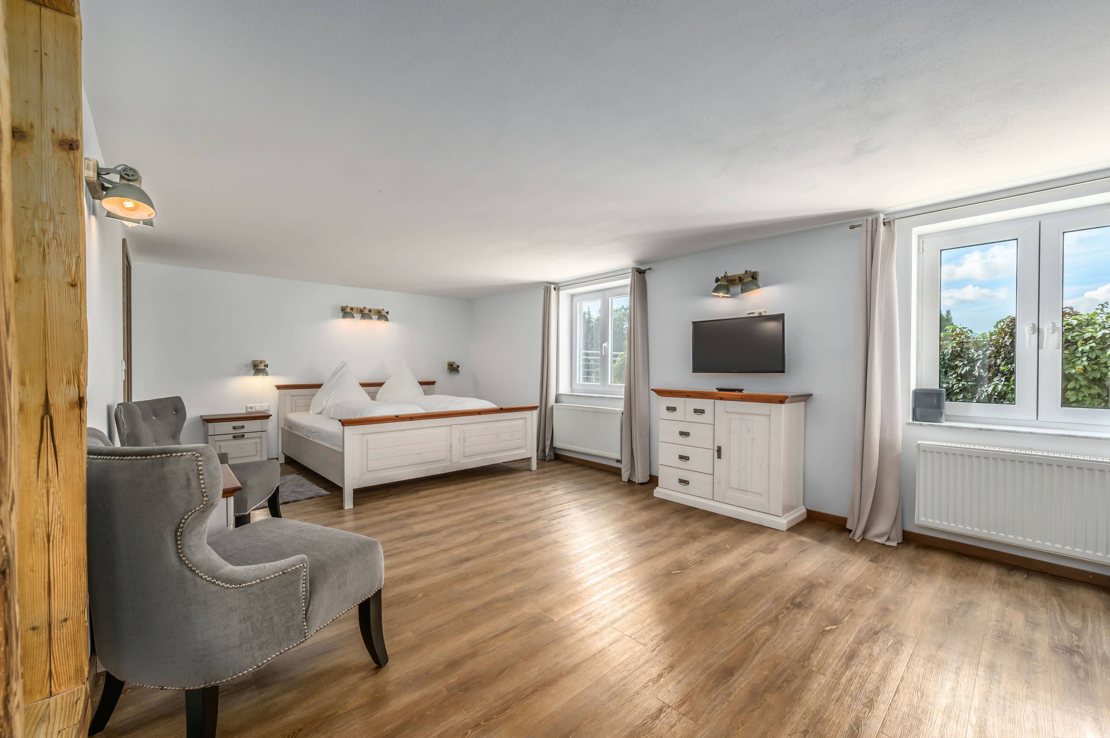Ein Schlafzimmer mit Bett, Nachttischen, Fernseher und Fenster.