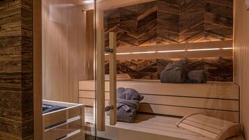 A sauna with wooden benches, a glass door, and a herringbone-patterned wall.