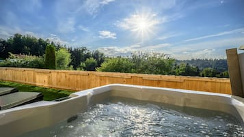 Ein Whirlpool mit Holzzaun und Bäumen im Hintergrund.