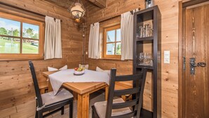 A wooden interior with a round table, chairs, and a hanging light fixture.
