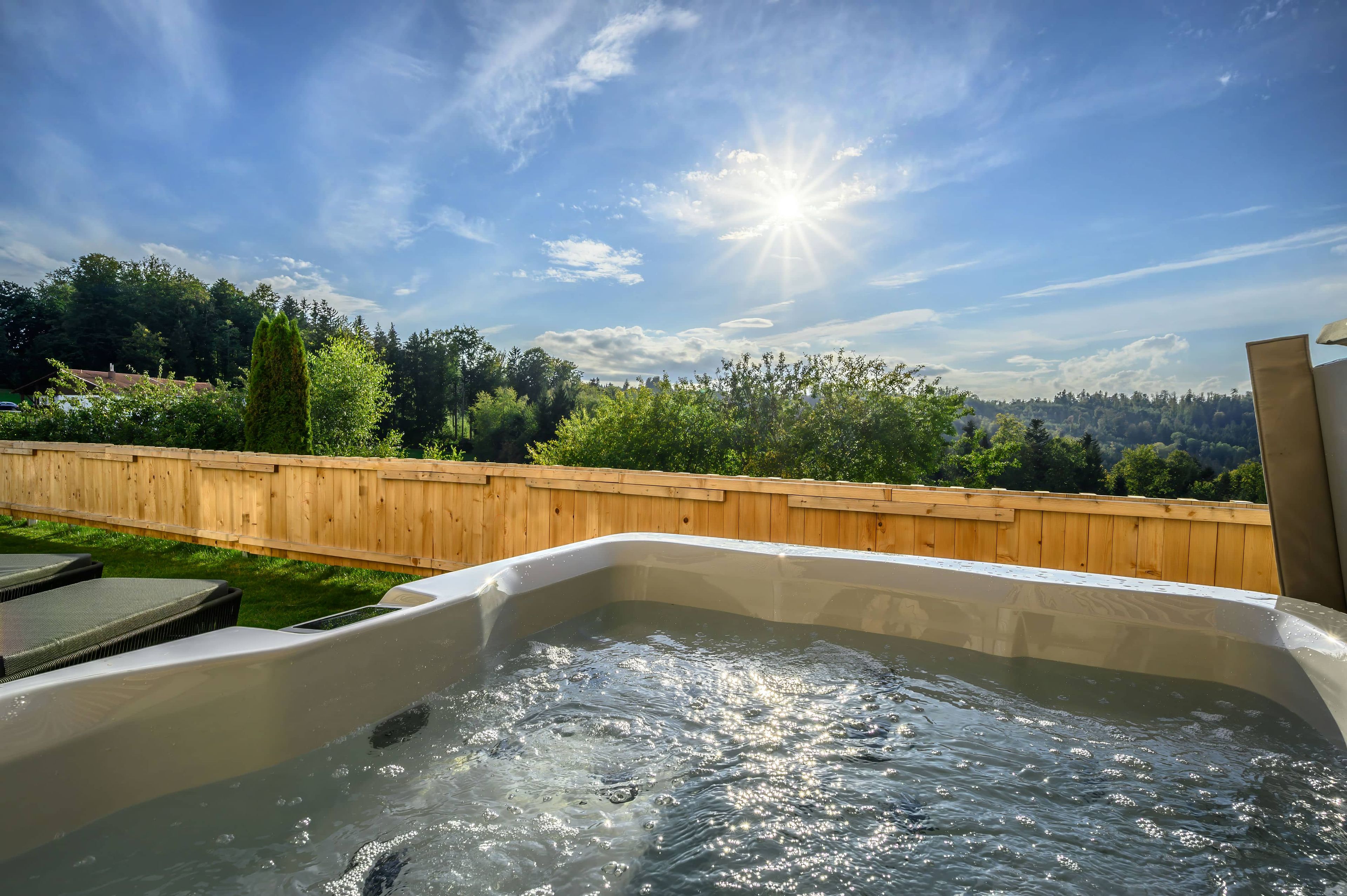 Ein Whirlpool mit Holzzaun und Bäumen im Hintergrund.