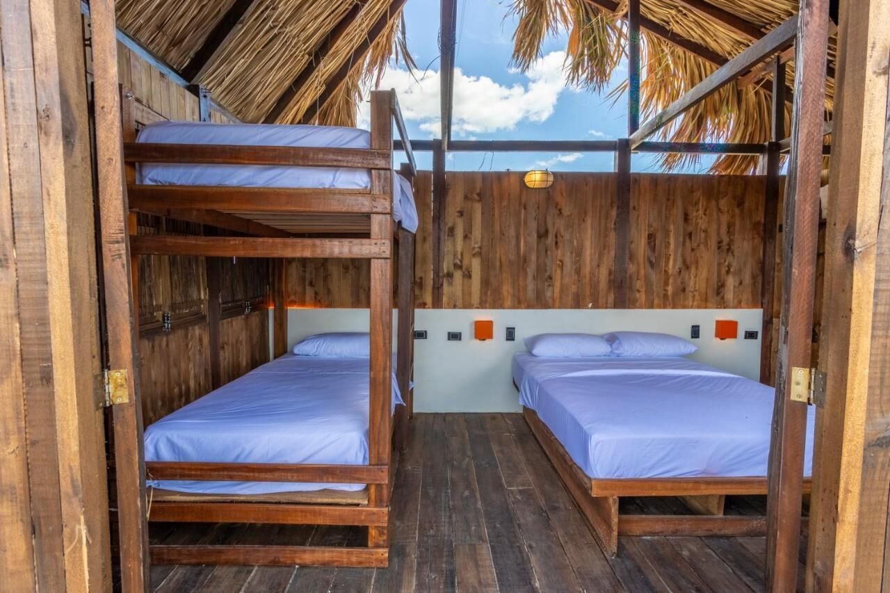A wooden cabin with bunk beds, a thatched roof, and a view of the sky.