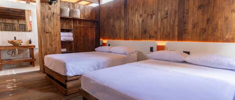 A wooden room with two beds, a wooden bench, and a fan.