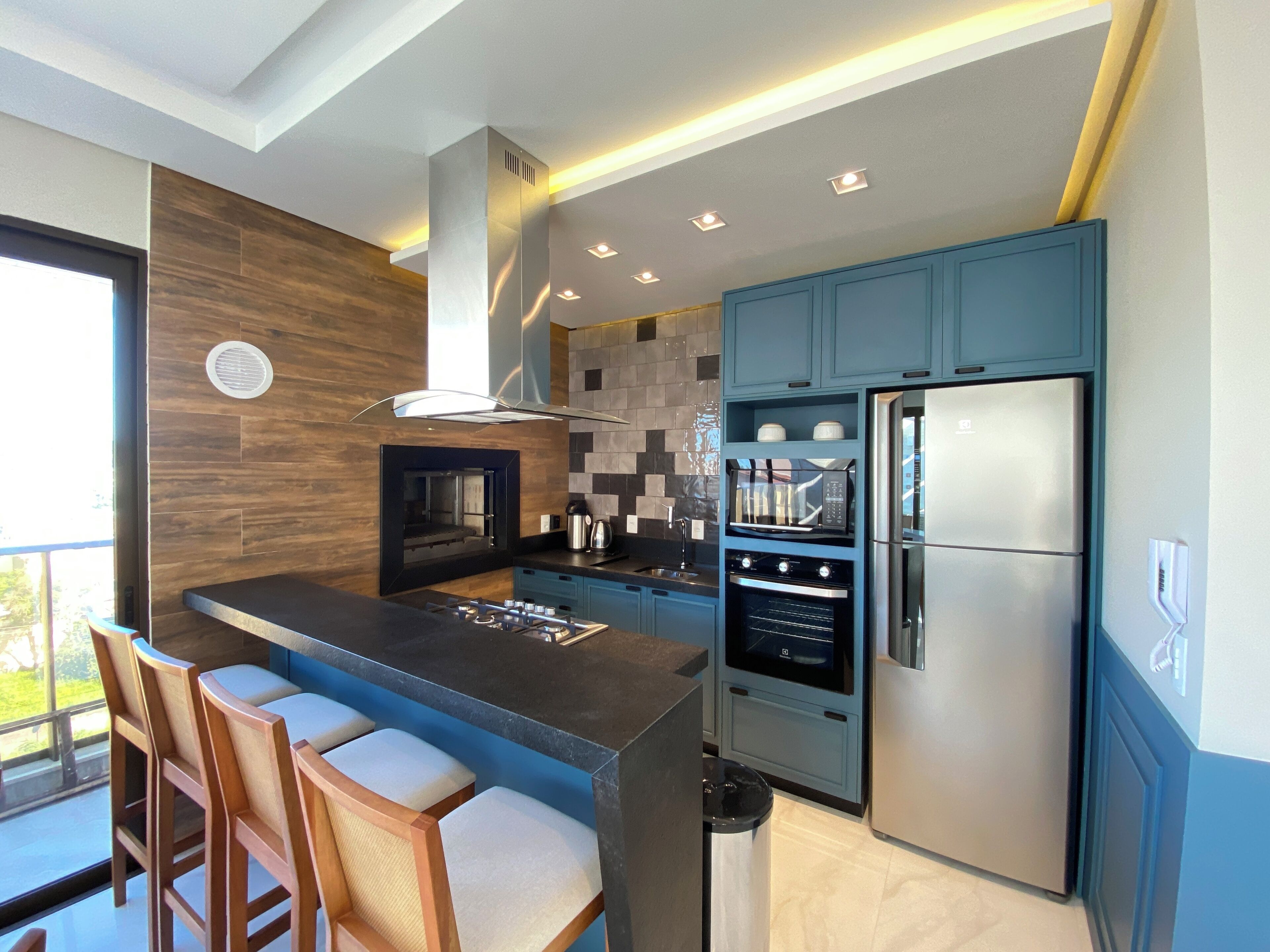 Una cocina moderna con una isla central, horno empotrado, microondas y refrigerador.