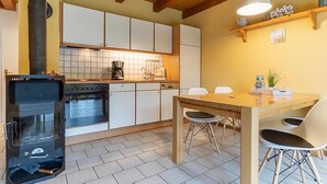 A modern kitchen with white cabinets, a wooden table, and a built-in oven. - Landhaus in Vollerwiek (Vollerwiek)