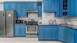 Een moderne keuken met blauwe kastjes, roestvrijstalen apparatuur en een wit aanrecht.