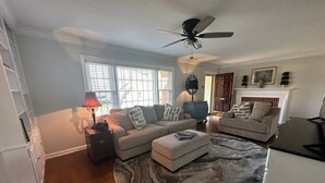 A living room with a round marble rug, two sofas, a ceiling fan, and a fireplace.