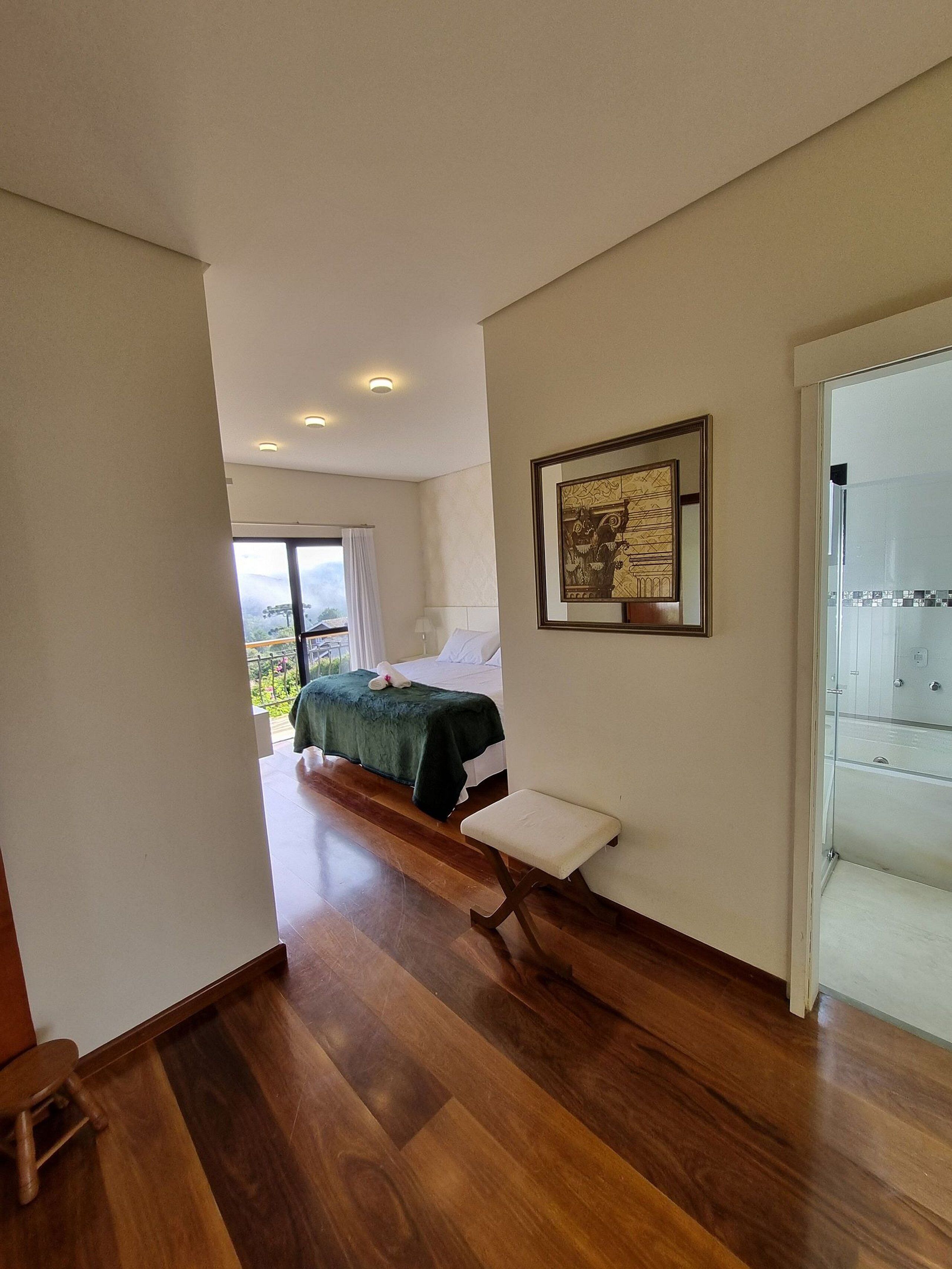 Une chambre à coucher avec un lit, un banc, un tableau encadré et une vue sur l’extérieur.