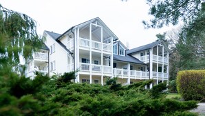 A multi-story building with balconies, surrounded by dense greenery.