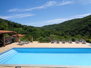 A swimming pool with lounge chairs and a view of a forested valley. - Beautiful Wedding venue for a destination wedding in Italy with pool, 32-50 pers (Bonvicino)