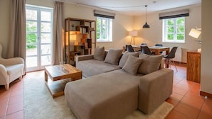 Una sala de estar moderna con un sofá seccional, una mesa de centro de madera, una estantería y un comedor con sillas y una mesa.