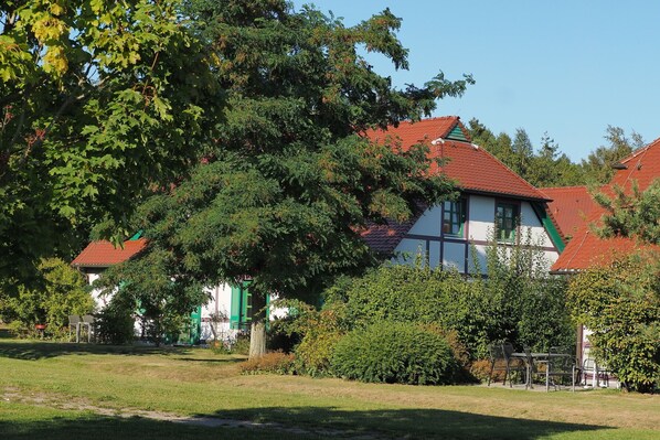 A traditional building with a red-tiled roof, surrounded by lush greenery and a well-maintained lawn.