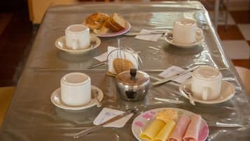 A breakfast table with cups, a teapot, and plates of food.
