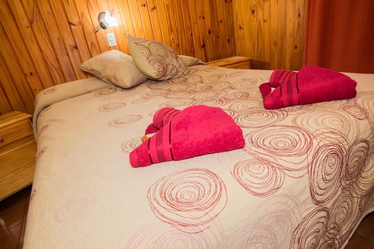 Un lit avec une couvre-lit à motifs, deux oreillers et deux serviettes pliées.
