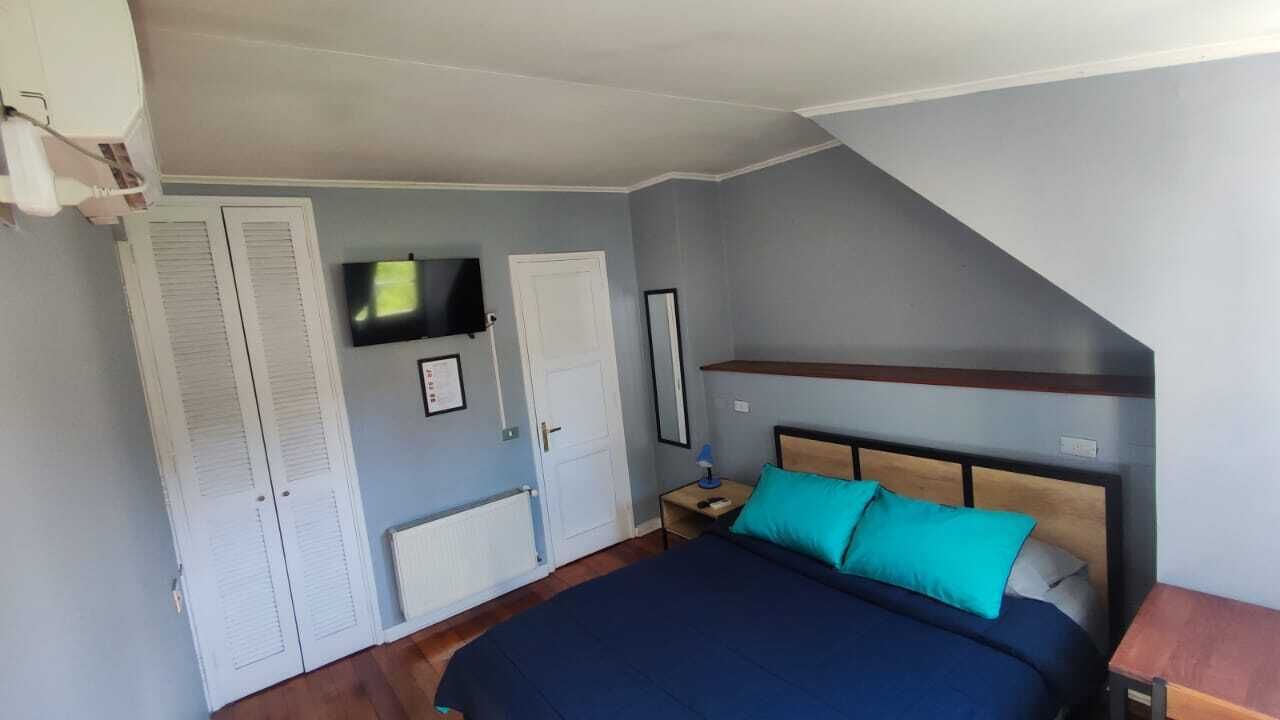 A bedroom with a bed, a TV, a wardrobe, and a small table.