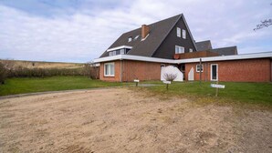 A modern two-story house with a brick exterior and a sloped roof. - Ferienwohnung in St. Peter-Ording (St. Peter-Ording)