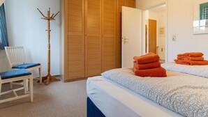A hotel room with a bed, a chair, a coat rack, and a wardrobe.