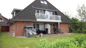 A two-story house with a balcony, a garage, and a well-maintained lawn.