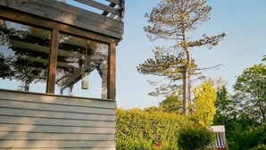 A wooden building with a pergola and a small garden area with a bench and a planter. - Ferienwohnung in St. Peter-Ording (St. Peter-Ording)