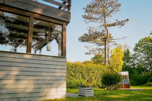 A wooden building with a pergola and a small garden area with a bench and a planter.