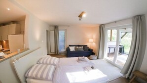 A bedroom with a bed, bedside table, lamp, and a view of the outdoors through a window. - Ferienwohnung in St. Peter-Ording (St. Peter-Ording)