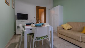 A compact living space with a dining table, chairs, a sofa, a television, and a cabinet. - Casa Antonelli by Wonderful Italy (Turin)