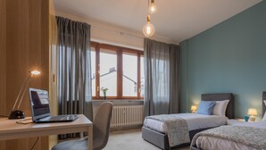 A hotel room with two beds, a desk with a laptop, a chair, and a window with curtains. - Casa Antonelli by Wonderful Italy (Turin)