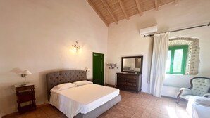 Un dormitorio con cama, cómoda, silla y espejo, y una puerta verde.