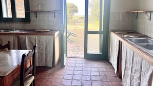 Una cocina con una mesa de comedor, sillas, un fregadero y una ventana que da a un jardín.