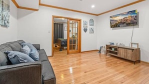 A living room with a wooden floor, a grey sofa, a wooden cabinet, and a painting on the wall.