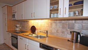 A modern kitchen with white cabinets, a stainless steel sink, a coffee maker, and a kettle. - Feldblick-Wohnung in der Nהhe der Ostsee (Schlagsdorf)
