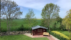 A wooden cabin with a sloped roof, a bench, and a stone wall. - Feldblick-Wohnung in der Nהhe der Ostsee (Schlagsdorf)