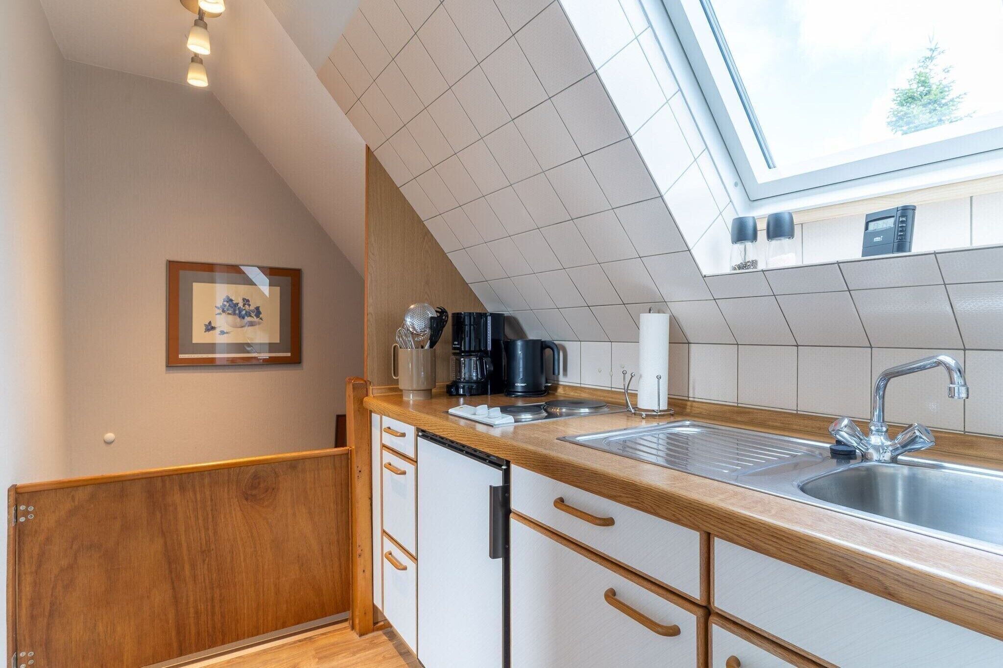 Una cocina con mostrador de madera, un lavamanos y una ventana sobre el lavamanos.