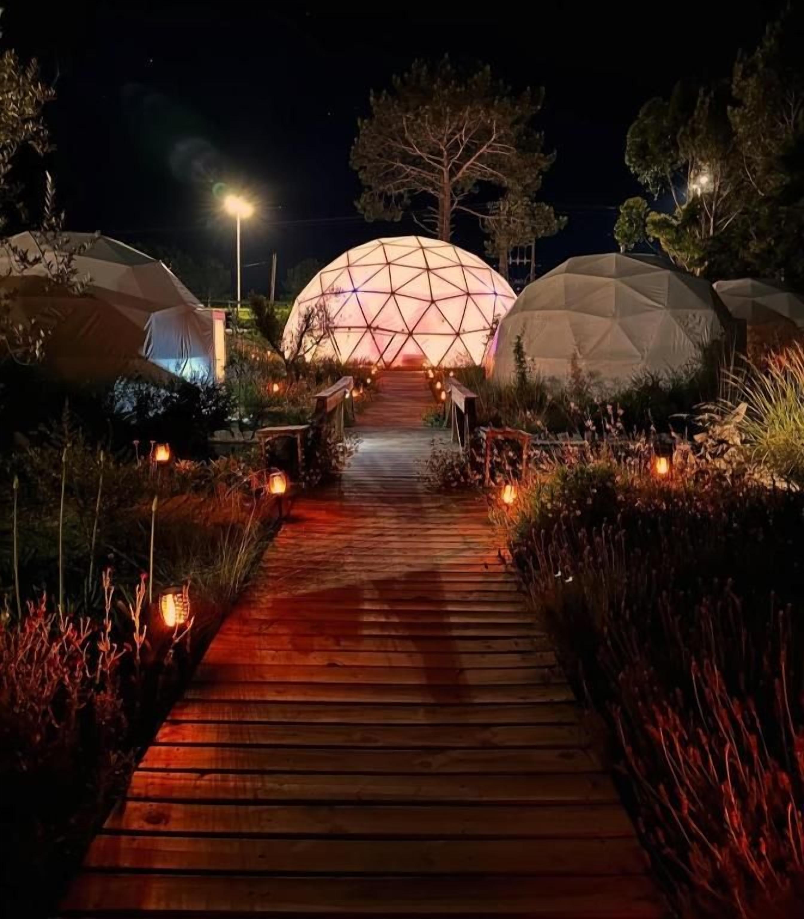 A pathway leading to geodesic dome structures at night.
