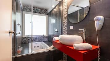 A modern bathroom with a glass-enclosed shower, a large mirror, and a red vanity with a towel.