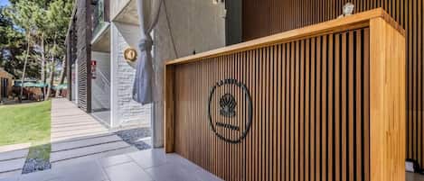 Una recepción con logotipo, una pared de listones de madera y un revestimiento de piedra.