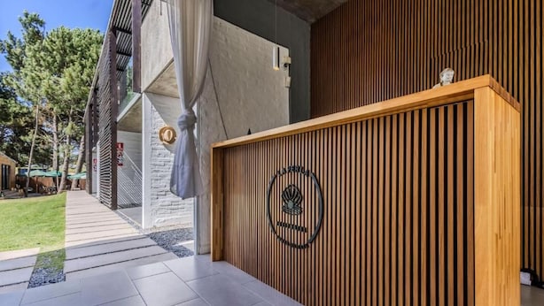Una recepción con logotipo, una pared de listones de madera y un revestimiento de piedra.